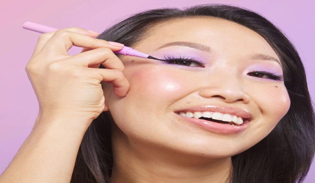 Woman applying adhesive eyeliner on her upper lash line